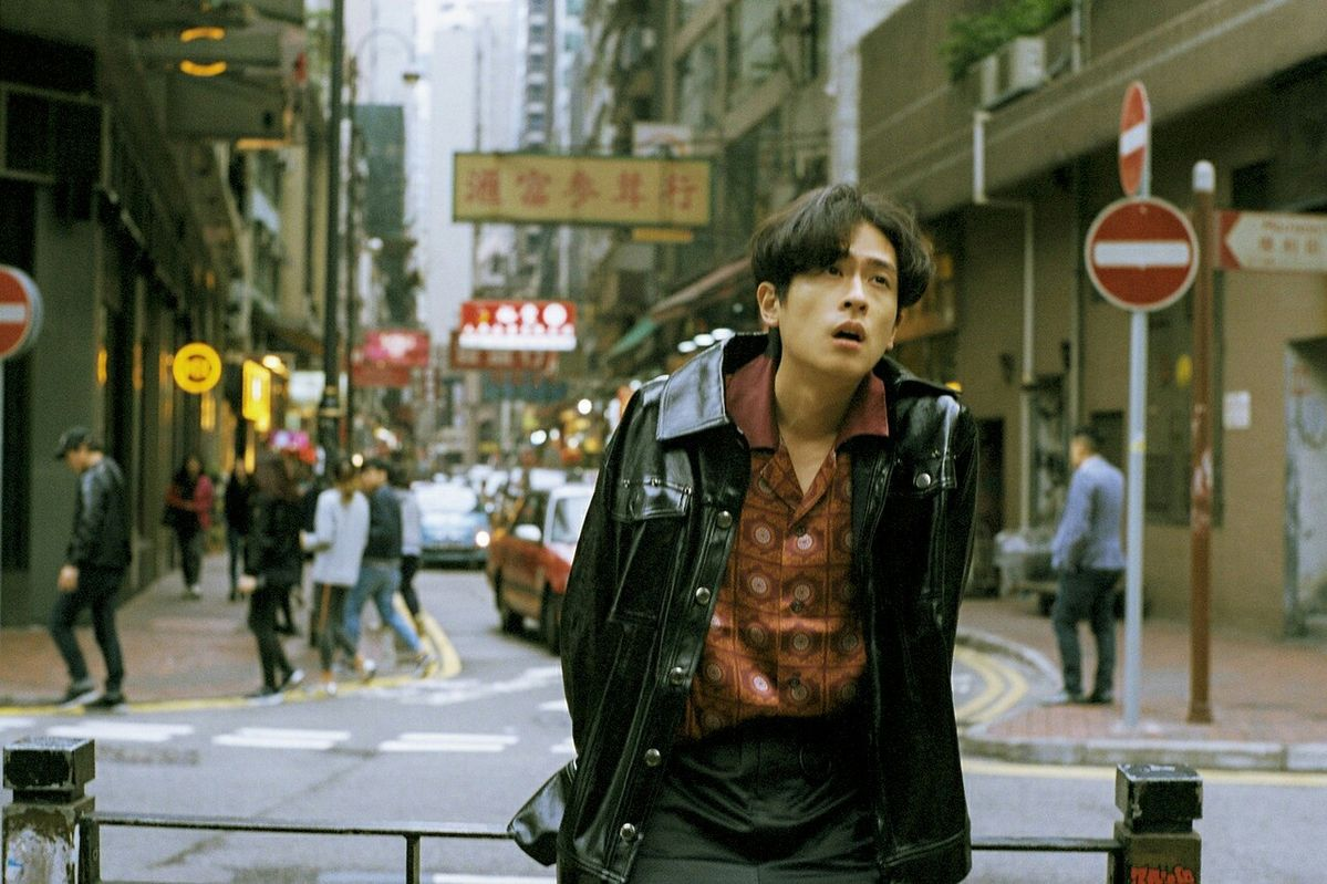 A man in a leather jacket against a softly blurred city street
